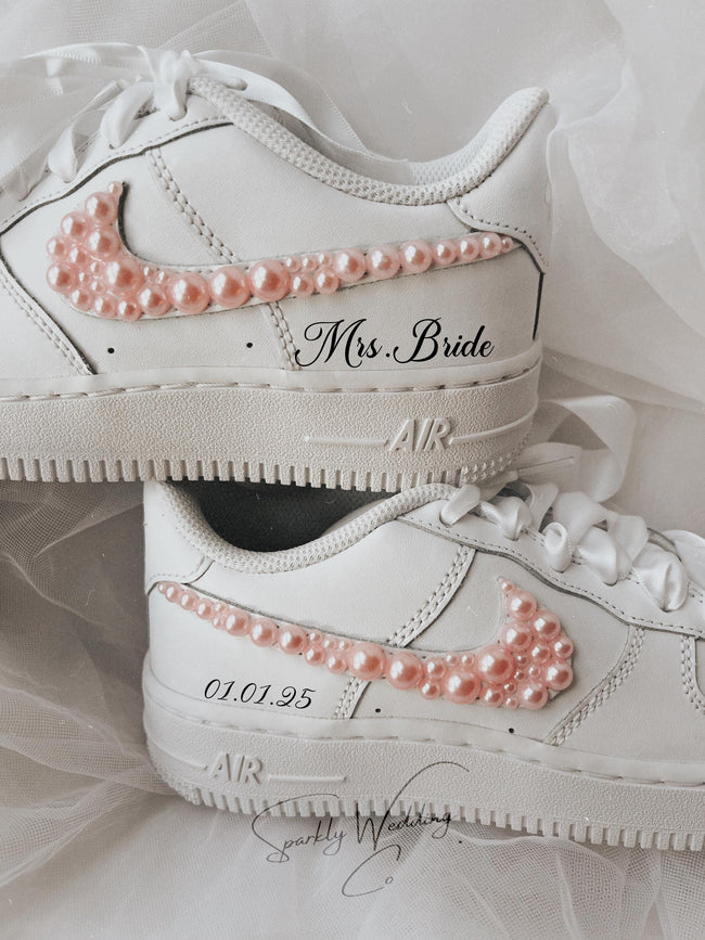 Close-up of pink pearl embellishments on the outer swoosh of bridal wedding sneakers
