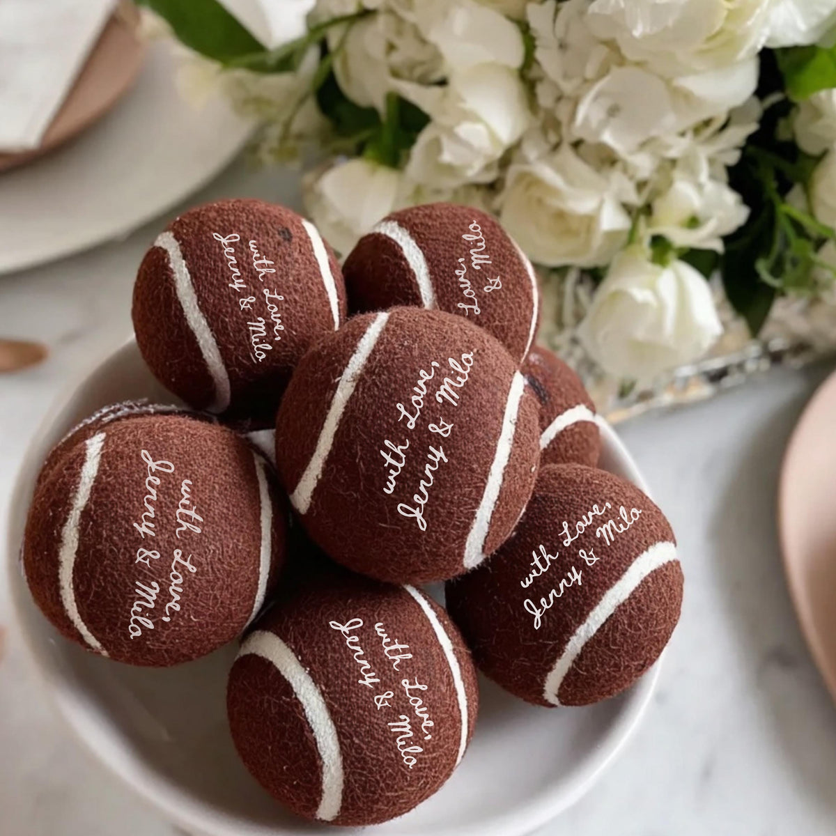Custom tennis balls styled as wedding favors on a clean flat lay background